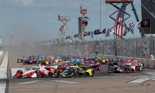 NTT IndyCar Series drivers race three wide at the start of the Firestone Grand Prix of St. Petersburg on the downtown street circuit along the St. Pete waterfront.
