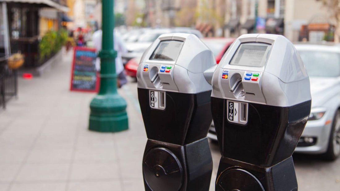 Two electronic parking meters along a busy city street illustrate rising St. Pete parking fines and permit fees following St. Petersburg City Council's approval of higher parking penalties in October 2026.