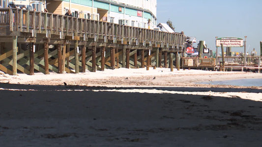 Sandy shoreline and boardwalk at John’s Pass Village in Madeira Beach before dredging project removes built up sandbar.