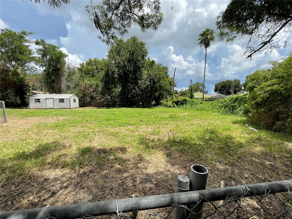 Vacant residential lot in St. Petersburg, Florida, showing open grassy space and surrounding trees, illustrating properties that could be impacted by flood recovery plans and potential disaster buyout programs.