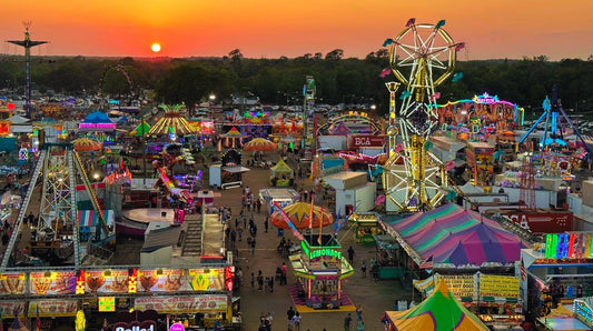 Aerial sunset view of the 2026 Florida Strawberry Festival midway in Plant City with Ferris wheel, carnival rides, food tents and crowds attending the annual Tampa Bay spring event