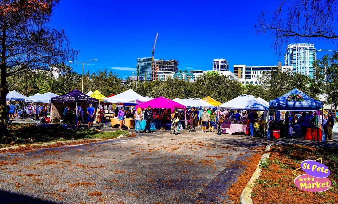St. Pete Sunday Market vendor tents set up at the USF St. Petersburg campus in downtown St. Petersburg Florida with shoppers browsing local vendors and city skyline in the background