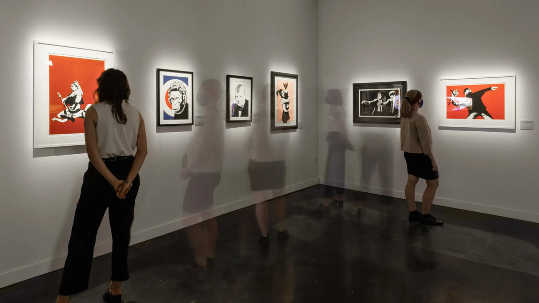 Visitors walking through a modern gallery space viewing multiple Banksy artworks on display during The Art of Banksy exhibit at the Straz Center in Tampa