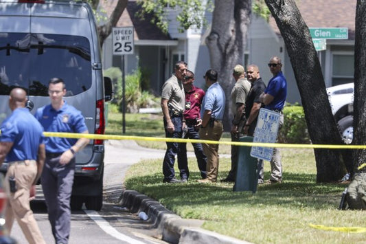Law enforcement officers gathered behind police tape in Tampa neighborhood as investigators respond to USF-connected murder case scene